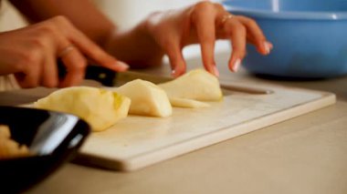 Mutfakta bir armudu kesme tahtasının üzerinde ellerinde bir bıçakla dilimlemek.