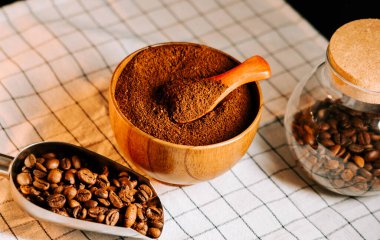 İçinde fasulye ve kumaş kepçesi olan ahşap bir kasede öğütülmüş kahve.