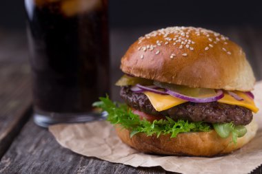 Ahşap arka plan üzerinde soğuk kola ile sulu burger