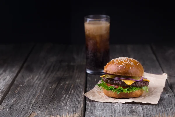 Soczysty Burger z zimną Cola na drewnianym tle — Zdjęcie stockowe