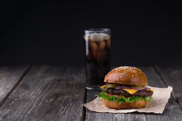 Soczysty Burger z zimną Cola na drewnianym tle — Zdjęcie stockowe