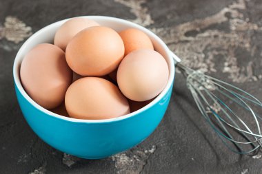 Taze tavuk yumurta bir kase bir beton backgrou üzerinde bir çırpma teli ile