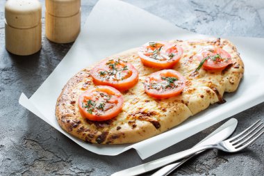 Peynir ve domates, otlar baharat, çatal bıçak takımı bir concr üzerinde pizza