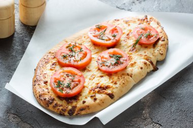 Pizza peyniri ve kırmızı domates, yeşil baharatlar ile
