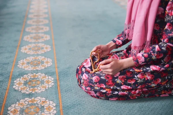 Flicka sitter sorterar Träpärlor i en moské i blommig klänning, Muslim — Stockfoto