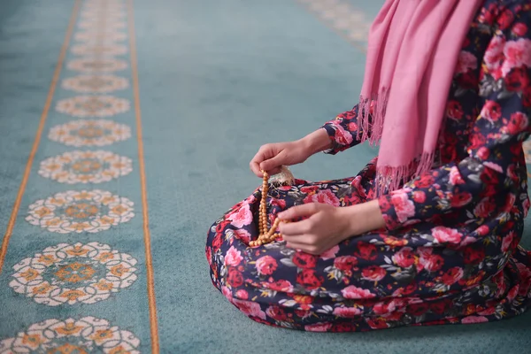Flicka sitter sorterar Träpärlor i en moské i blommig klänning, Muslim — Stockfoto