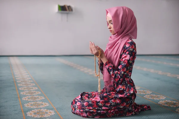 Dziewczyna siedzi sortuje drewniane koraliki w meczecie w kwiatowy strój, młody Muzułmanin, siedząc w kierunku Qibla, jej ręce przed jej błagania, kończące modlitwy, świadectwa, modlitwa Rukn — Zdjęcie stockowe