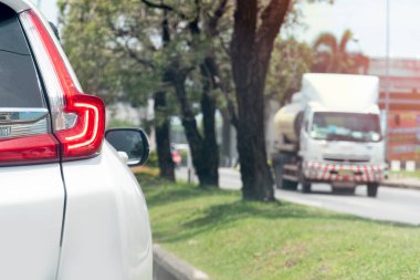 Fren lambalı beyaz arabanın yakın çekim ışığı. Ağaçlar ve camlarla yol kenarına park etmek. Seyahat zamanı ve gevşeme zamanı.