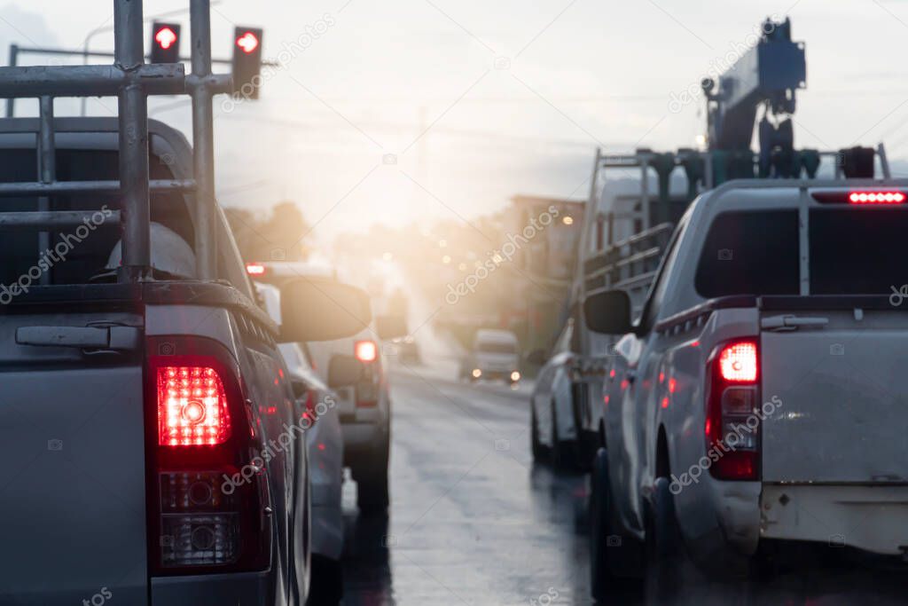 Rear side of cars stop and turn on brake light. Environment of asphalt road on rainy time. Intersections with red traffic lights to indicate stop.