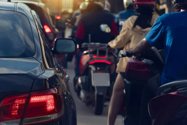 Rear side of black car with turn on brake light. Heavy traffic congestion in a city with blurred o f sedan cars and motorcycle.