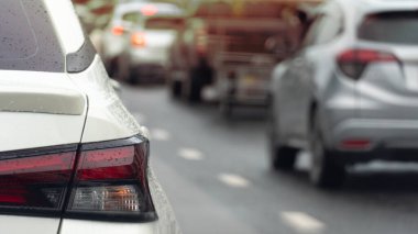 Rear side of white car driving on the road. On body of car with drop of water rain. Blurred of cars driving in line on the wet asphalt road.