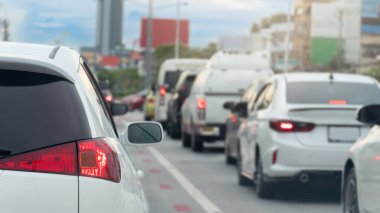 Rear side of white luxury car with turn on brake light. Traffic jam on the road. Many car queue up in traffic jams in the city at day time.
