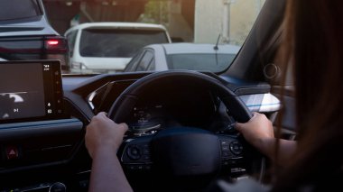 Arabanın içinde araba süren kadınlar direksiyonu sıkıca tutarlar. Trafik kavşağında yolda bir sürü araba var. Yolda bir sürü araba kuyruğu var..