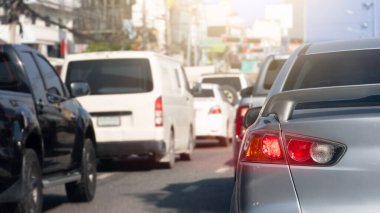 Gümüş arabanın arka tarafında fren lambası açık. Parlak ışık huzmeleriyle. Şehir asfalt yollarında trafik sıkışıklığı.