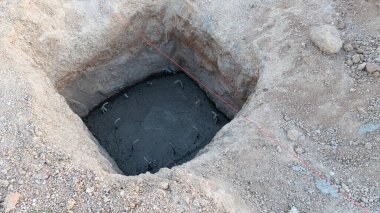 Ev inşaatı için zemine kazılan Meydan Vakfı 'nın eğim açısı. Kazının dibi burası. Kalın ıslak çimento tabakası temel olarak kullanılıyor..