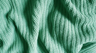Örgü örülmüş battaniye ya da parlak bir nane, zümrüt ya da turkuaz renkte süveter dokusu. Sonbahar, kış ya da tatil kavramları için sıcak bir arka plan. El örgüsü, dikey dikiş deseni.