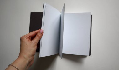 Kadının elinde açık bir defter var. Arkaplanda beyaz sayfalar var. Fikir kavramı, öğrenme, iş, yeni bir proje. Resim, modeller, kopyalama alanı ve eğitim temaları için uygundur.