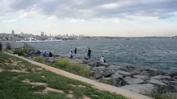 Menschen entspannen sich am steinigen Strand — Stockvideo