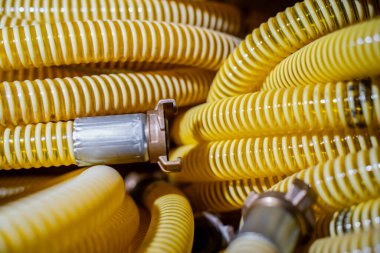 İnşaat ve mühendislik uygulamalarında gaz, hava veya su sistemleri için kullanılan metalik donanımlı sarı kıvrımlı endüstriyel hortumlara yakın çekim