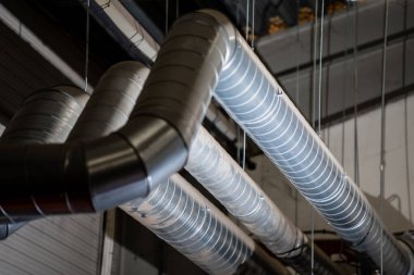 Endüstriyel tavana kurulmuş metal havalandırma kanalları ve havalandırma boruları HVAC sistem bileşenlerini, hava dağıtım teknolojisini ve fabrika için mekanik kurulumu gösteriyor.