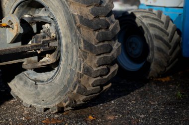 Çakıl taşı yüzeyinde duran inşaat makinelerinin üzerindeki büyük engebeli lastikler endüstriyel off-road ekipmanlarının gücünü, dayanıklılığını ve performansını temsil ediyor.