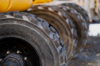 Açık hava projelerinde güç, güvenilirlik ve yer performansını temsil eden sarı inşaat aracında sıralanmış büyük endüstriyel lastikler.