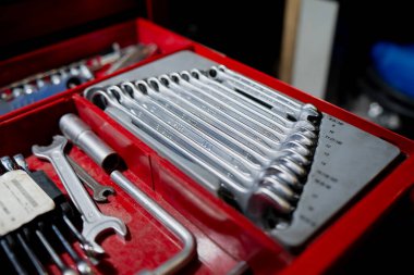 Bakım, atölye onarımı ve profesyonel el aletlerini temsil eden kırmızı alet kutusunda metal anahtarlar ve soketler bulunan organize mekanik araç seti