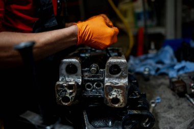 Tamir atölyesinde, inşaat malzemeleri bakımı, profesyonel mekanik servisi ve makine bakım sürecini temsil eden eldiven tamircisi.