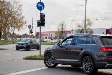 Trafik ışıkları altında şehir kavşağında bekleyen modern SUV ve kompakt arabalar kontrollü araç hareketleri, şehir ulaşım sistemi ve düzenlenmiş yol altyapısı tasarımı gösteriyor.