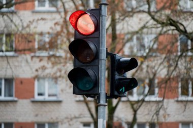 Şehir trafik lambaları, trafik kontrol sistemini, karayolu güvenlik mekanizmasını ve düzenlenmiş ulaşım altyapısını temsil eden yerleşim alanı arka planına yönelik kırmızı ışığı gösteriyor.