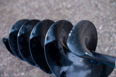 Islak çelik matkap ucu, basınçlı yıkama sonrası su damlacıklarıyla temiz spiral bıçakları gösteriyor. Yer delme, temel inşaatı ve toprak kazma makineleri için kullanılıyor.