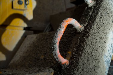 Kurumuş çamur ve tozla kaplı inşaat aracının kirli kırmızı sapı gerçek çalışma koşullarında ağır açık hava kullanımı, endüstriyel güç ve dayanıklılık belirtileri gösteriyor.