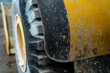 Çamur ve tozla kaplı ağır iş çarkları iş sahasının dayanıklılığını, yol çalışması ve toprak taşıma projelerinde kullanılan yükleyici veya kazıcının mekanik gücünü gösteriyor.