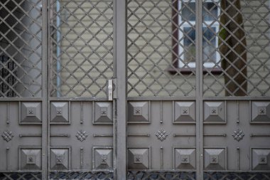 Çapraz desenli şebeke ve kabartmalı paneller ile süslemeli demir kapı geleneksel metal işçiliği, mimari koruma unsurunu ve konut mimarisinde ayrıntılı işçiliği gösteren