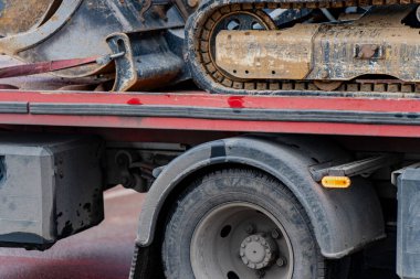 Taşıma, bakım ve endüstriyel nakliye işlemleri için lojistik işlemler sırasında taşımacılık kamyon platformunda kazıcı şasisi ile takip edilen inşaat ekipmanları