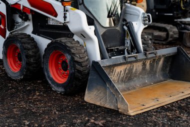 Dayanıklı mühendislik, hidrolik kaldırma sistemi ve modern makinelerin mekanik dayanıklılığını gösteren, inşaat ve sanayi projelerinde kullanılan büyük ön kovalı ağır kızak dümen yükleyicisi.