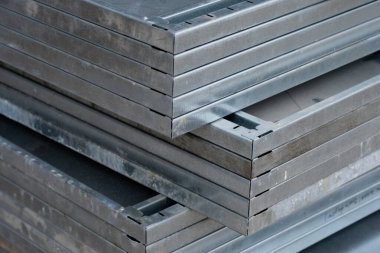 Sıkıştırılmış paket halinde istiflenmiş galvanize çelik paneller, hizalanmış katmanları, iç içe geçmiş kenarları ve ağır inşaat için hazırlanmış sert yüzeyleri gösterir