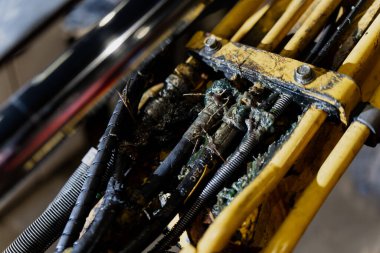 Kirlenmiş hidrolik hat montajı çözünmüş kaplama, çatlamış hortumlar ve birikmiş enkaz kalıntıları resimli ekipman giysisi, kayganlaştırıcı sızıntısı ve mekanik yönlendirme için gerekli hizmet