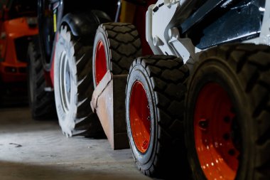 Depoya yerleştirilmiş çoklu inşaat araçları, dayanıklı tekerlek montajları, kalın lastik lastikleri ve çalışma alanı çekme ve manevra görevlerinde kullanılan dayanıklı kenar yapıları içeriyor.