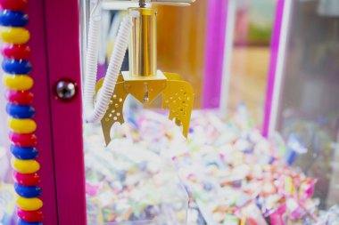 Altın atari pençesi bir pençe makine dolabında parlak ödüller yığını üzerinde asılı, eğlence oyun oynamak ve ödül geri alma girişimlerinde kullanılan mekanik yakalama aygıtı yakalamak