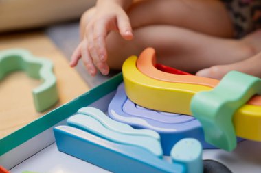 Döşeme oyununda çocuğun yanında kıvrımlı katmanlı yığın halinde organize edilmiş köpük öğrenme parçaları dokunsal etkileşim, yaratıcı aktivite ve erken gelişim bağlılık sahnesi sunuyor