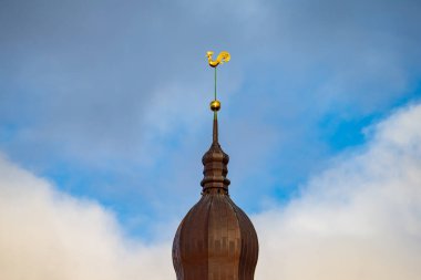 Eski şehir Riga Kubbesi 'nin çatısında, açık mimari manzaralı mavi ve beyaz gökyüzüne karşı yerleştirilmiş altın horoz süslemeleri bulunan yüksek kule bulunuyor.