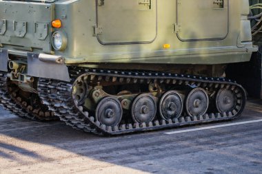 Metal yol tekerleklerini, süspansiyon sistemini ve hareketlilik ve yer destek operasyonlarında kullanılan sürekli pist tasarımını gösteren askeri bir aracın yakın görüntüsü.