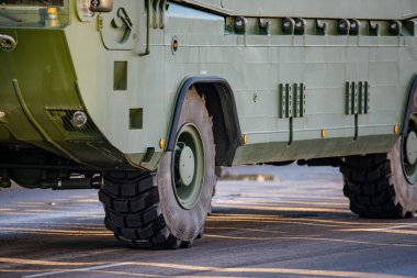 NATO müttefik askeri taşıma aracının geniş off-road lastikleri, güçlendirilmiş yan panelleri ve savunma faaliyetleri sırasında kentsel yol boyunca ilerleyen zırhlı dış görünüşü yakından görülüyor.