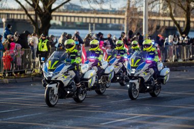 Yansıtıcı üniformalı motosikletli memurlar, halka açık geçit töreninde kalabalığın gözlediği gibi etkin ışıklarla kolluk kuvvetlerine eşlik ediyorlar.
