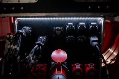 Çoklu numaralandırılmış prizler, endüstriyel bağlantılar ve engebeli kablolardan oluşan güç paneli, modern sahne inşaatını ve büyük olay güç sistemlerini destekleyen temel altyapıyı gösteriyor