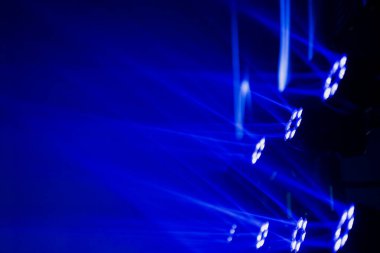 Baş LED armatürleri katmanlı mavi ışık desenleri ve süpürme kirişleri oluşturarak profesyonel bir üretim ortamı içinde soyut bir görsel şablon oluşturur.