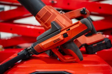 Modern bir inşaat ortamında kırmızı makinelere yerleştirilmiş ergonomik saplar, havalandırma yuvaları ve pil modülleri içeren kablosuz kırmızı güç araçları