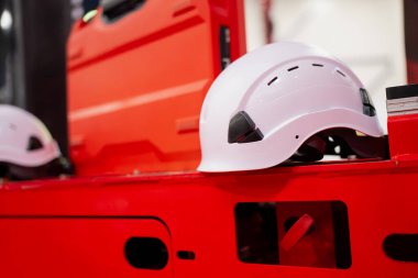 Beyaz güvenlik miğferi, parlak kırmızı endüstriyel makinelerin yüzeyinde duruyor, inşaat alanı koruyucu ekipmanları ve modern ekipman ortamını vurguluyor.