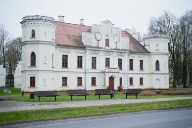 Letonya 'daki tarihi malikaneyi restore ettik. Dış görünüşü soluk. Detaylar ikiz kuleler ve binanın önündeki sessiz halk parkı.